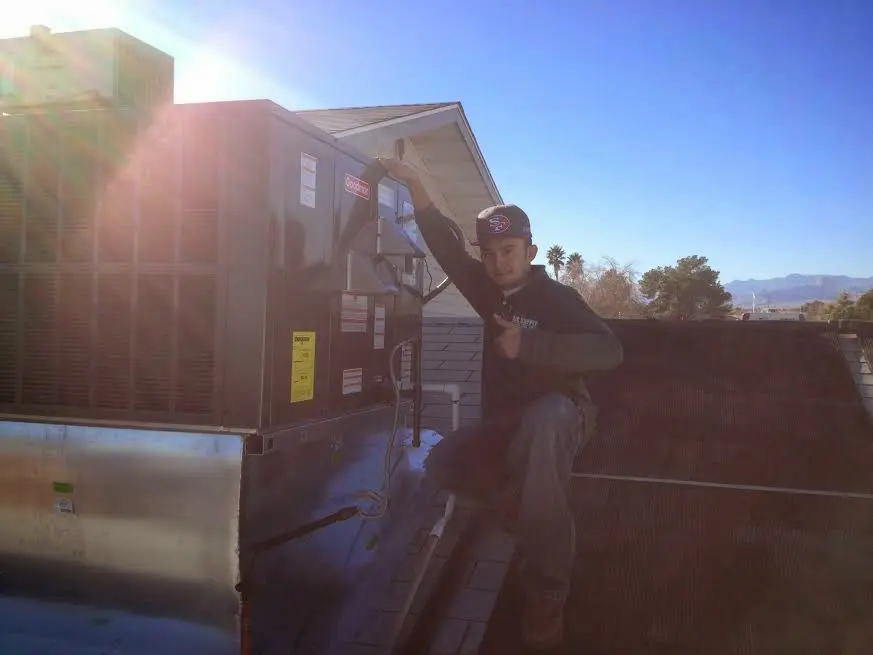 HVAC technician performing AC Tune-Up on a rooftop unit in Hull